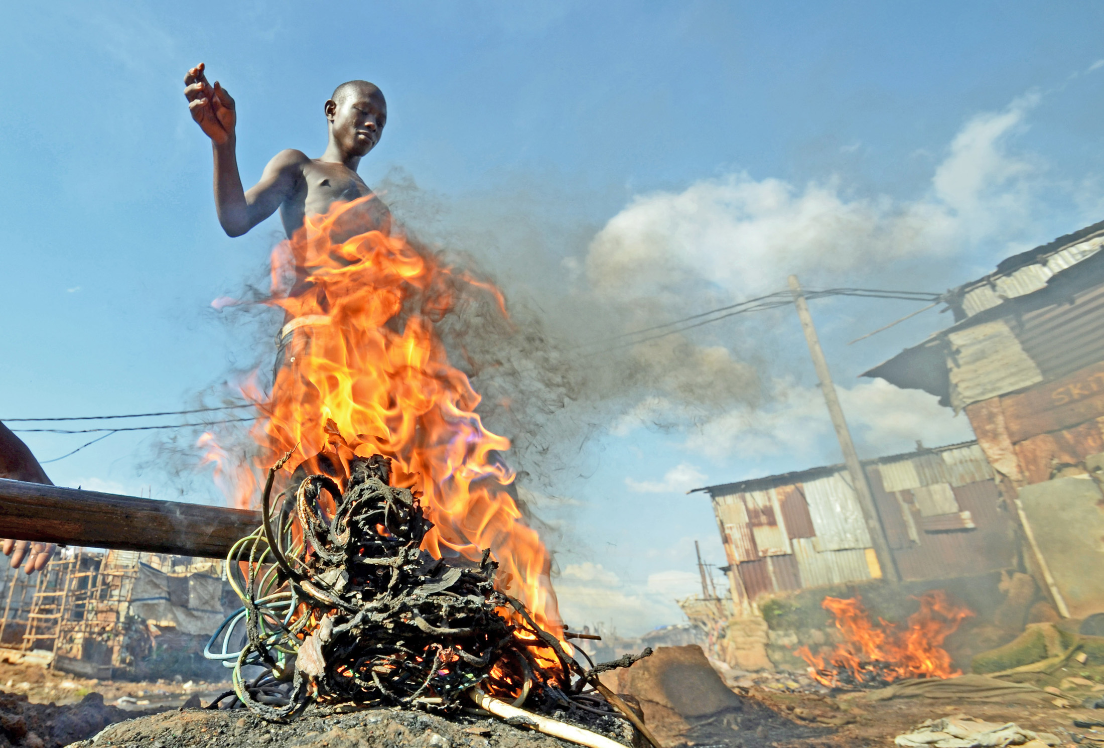 Mohammed Turay burns cables in Freetown’s Kroo Bay slum to extract copper which he sells as scrap