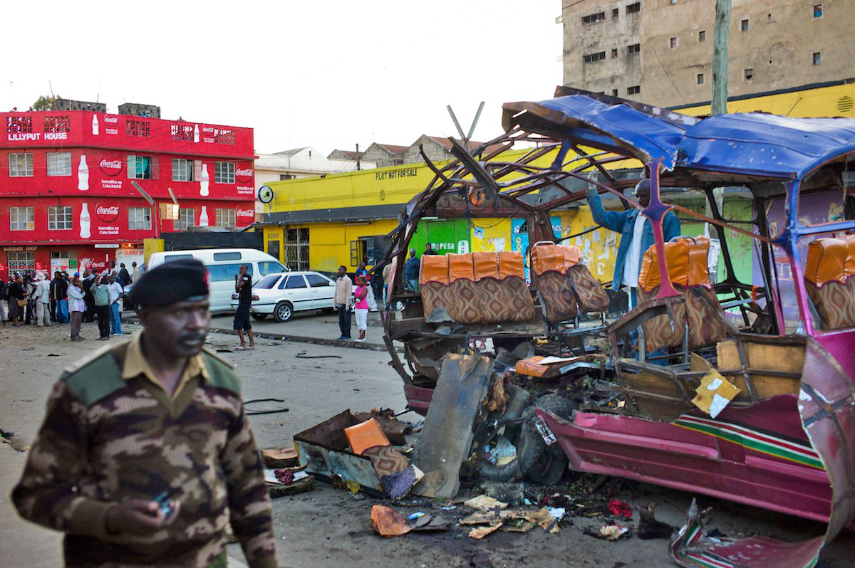A policeman walks past the remains of a public minibus blown up in the Eastleigh district of Nairobi on 18 November