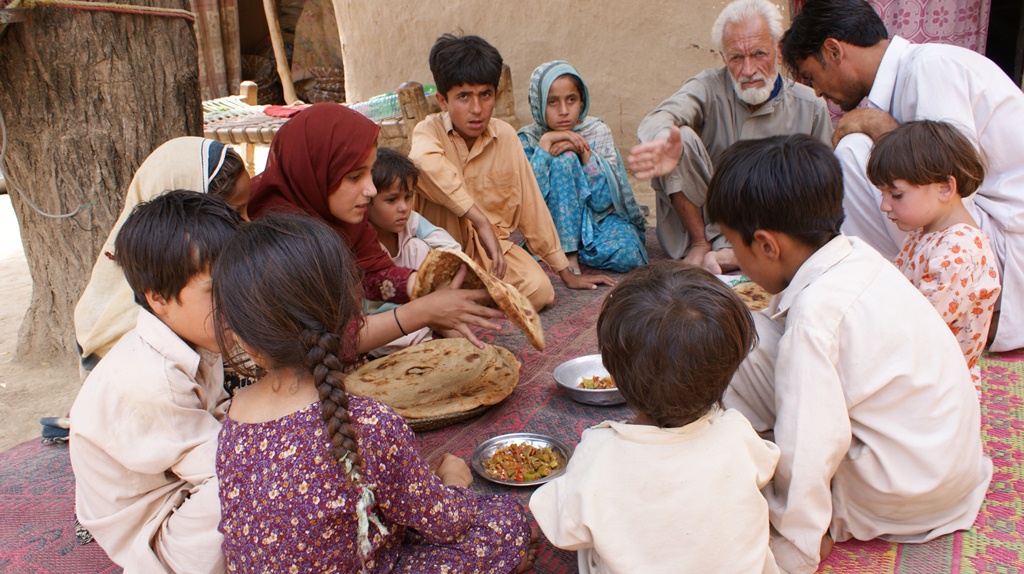 An IDP family living in a host community in Charsadda District, in the Pakhtunkhwa province of Pakistan, has lunch. The elder of the family just picked up their one-month ration from a WFP distribution point