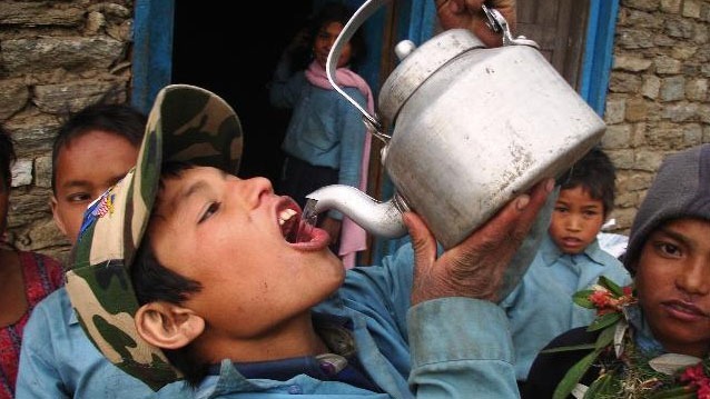 A young boys sips water from a teapot outside Jumla. The Karnali region is the poorest and least developed area of the country