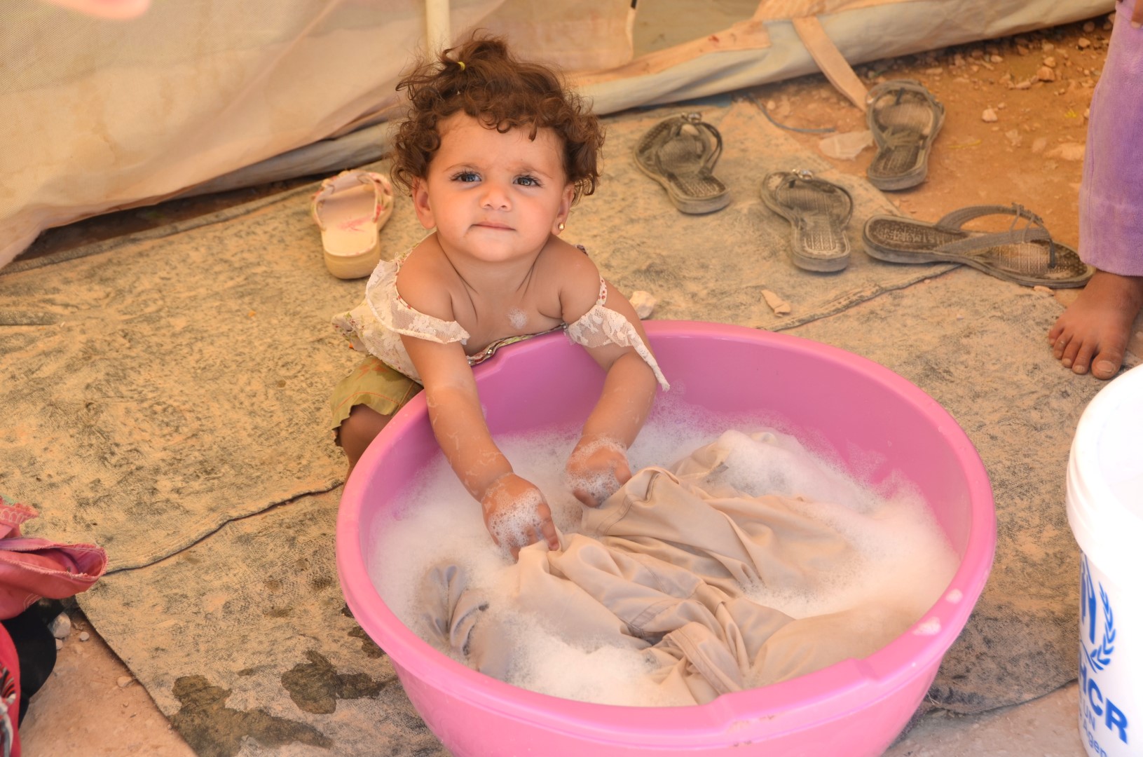 A Syrian refugee child plays with a tub of water in Jordan's Za'atari camp. Many Syrians - both inside and outside their country - cannot access enough clean water or sanitation