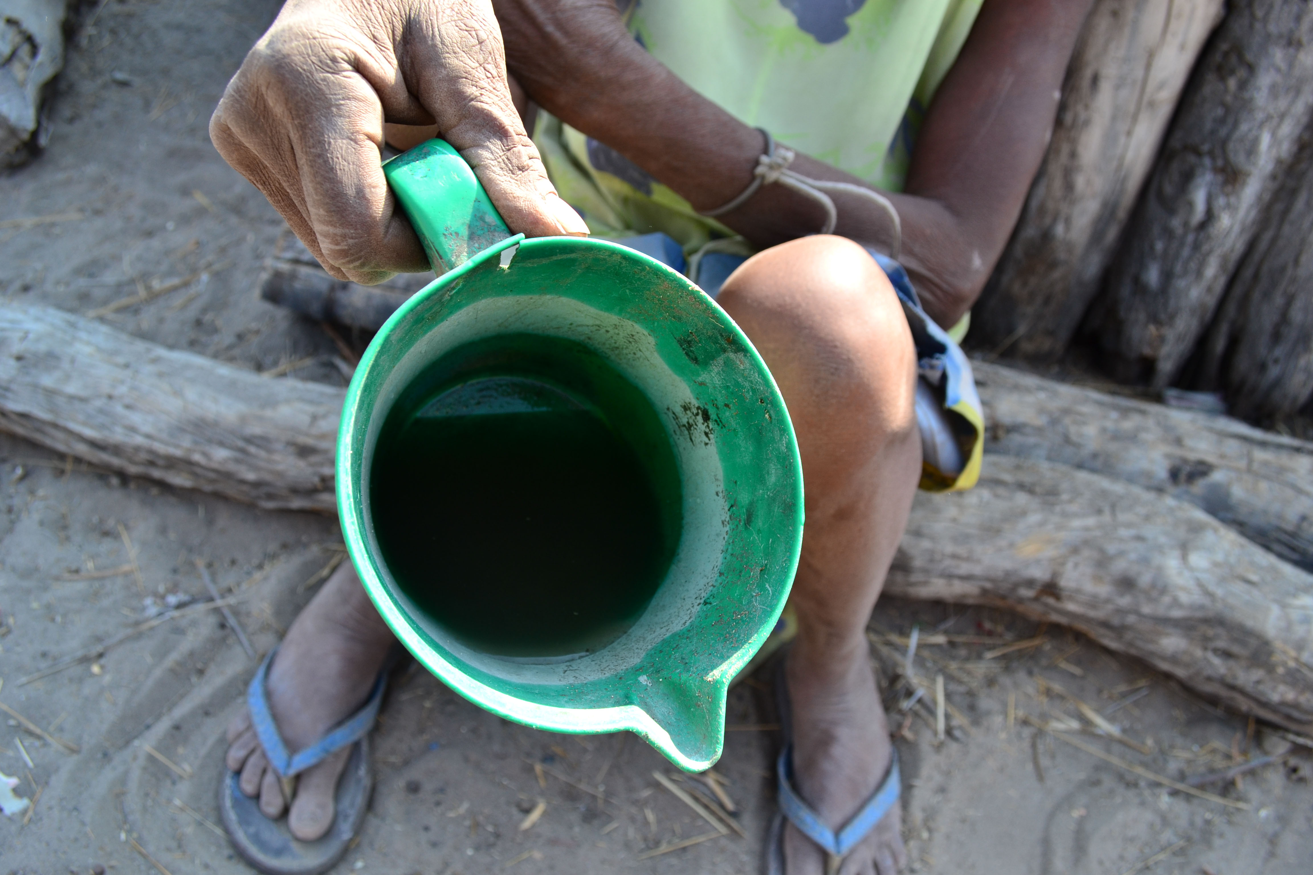 Victoria Nditondino holds up a jug of the dirty, brown water that her grandchildren have drawn from a distant well in southern Angola’s Cunene Province. Lack of rain caused the nearby well to dry up months ago