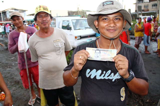 Bernard Morteja, 34, just received 500 pesos for one days work cleaning up debris and rubble off the streets of Tacloban from Taiwan-based Buddhist Tzu Chi Foundation, one a number of cash-for-work initiatives launched in the city in the aftermath of Typh