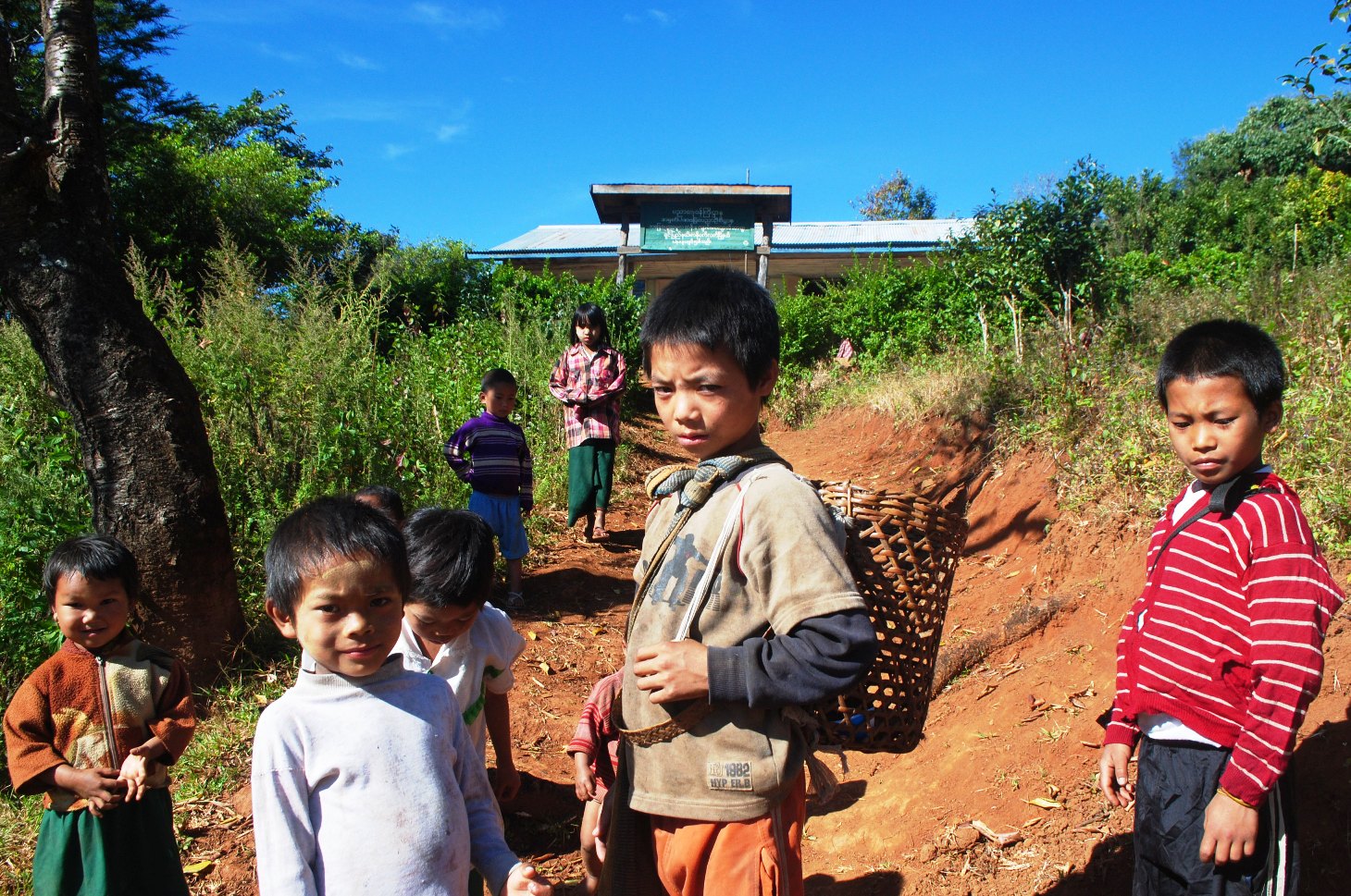 En route to school, some students are also prepared to head to the fields, demonstrating a tension for educators between school and home responsibilities for Chin State's schoolchildren