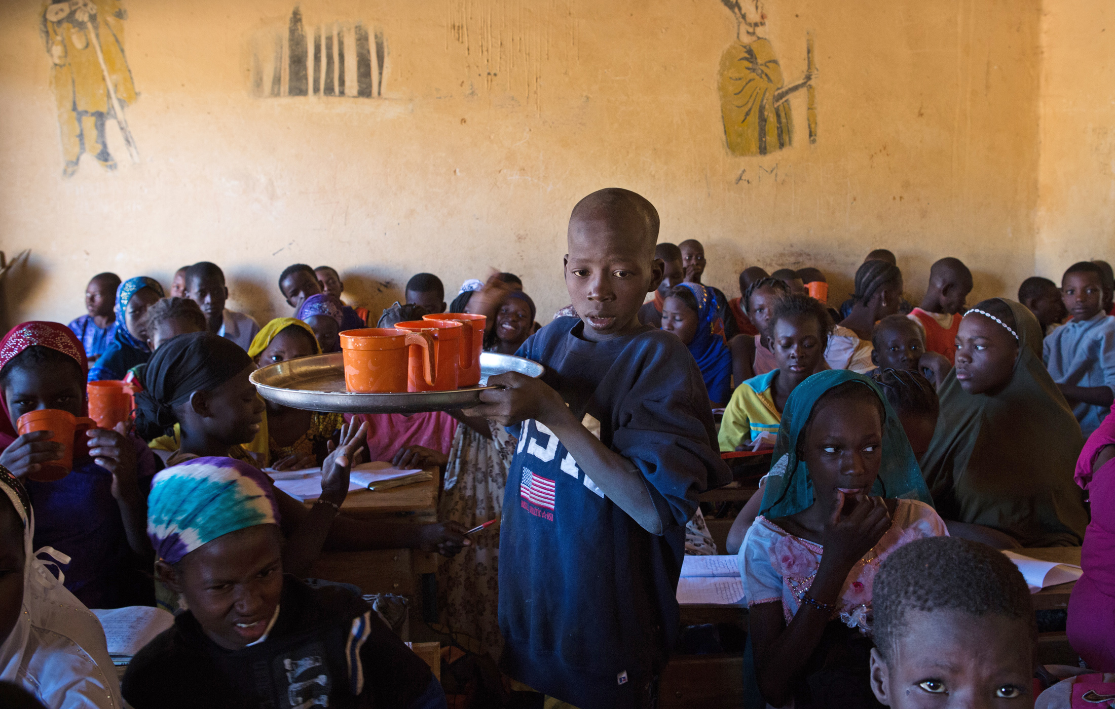 A student hands out meals to his fellow classmates in Gao, Mali. The World Food Program provides two meals a day to schools in Gao and other conflict-affected cities in northern Mali, such as Timbuktu. The emergency feeding program has seen a rise in atte