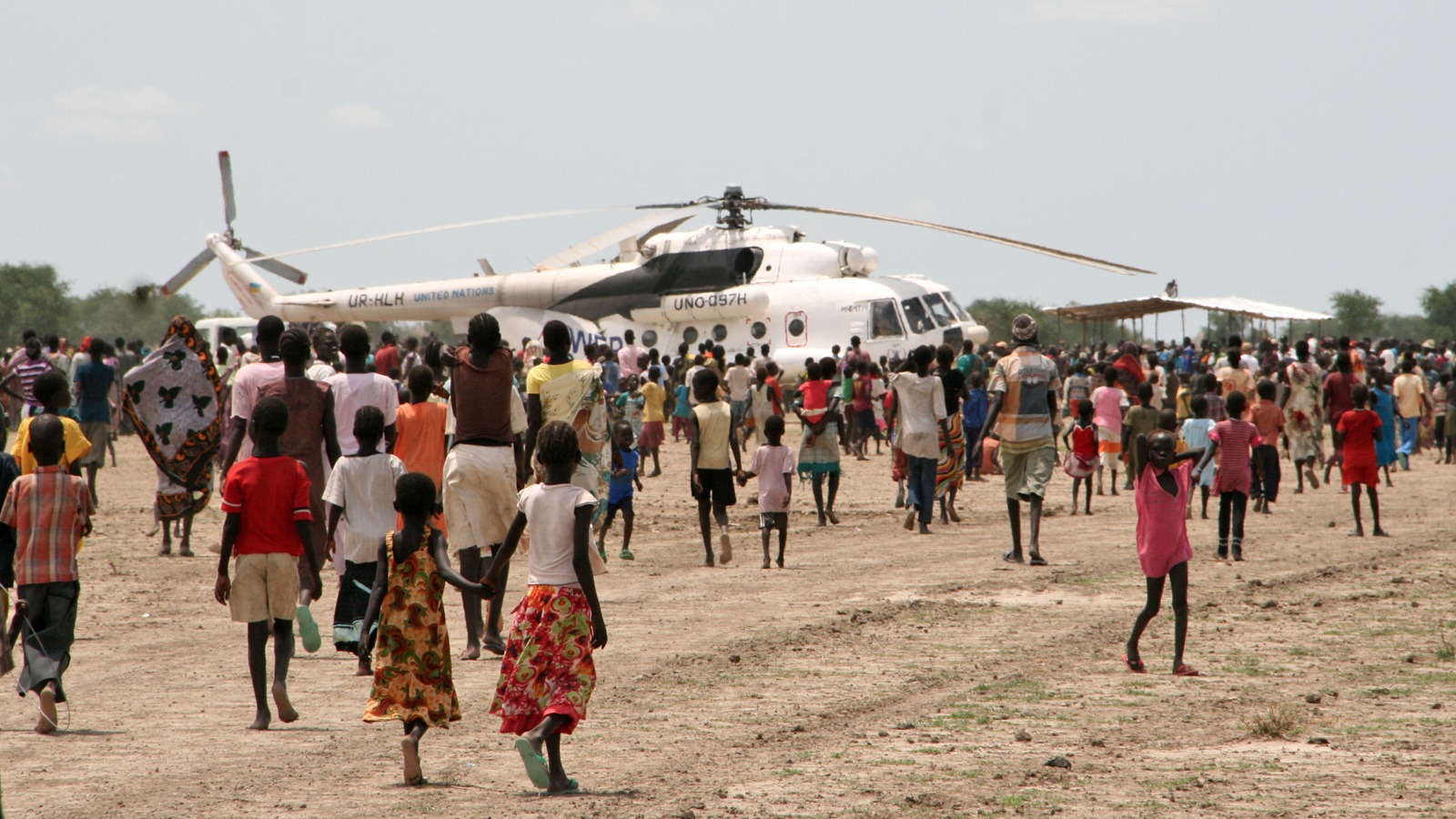 Displaced civilians crowd expectantly around a WFP helicopter in Wau Shilluk, Upper Nile State