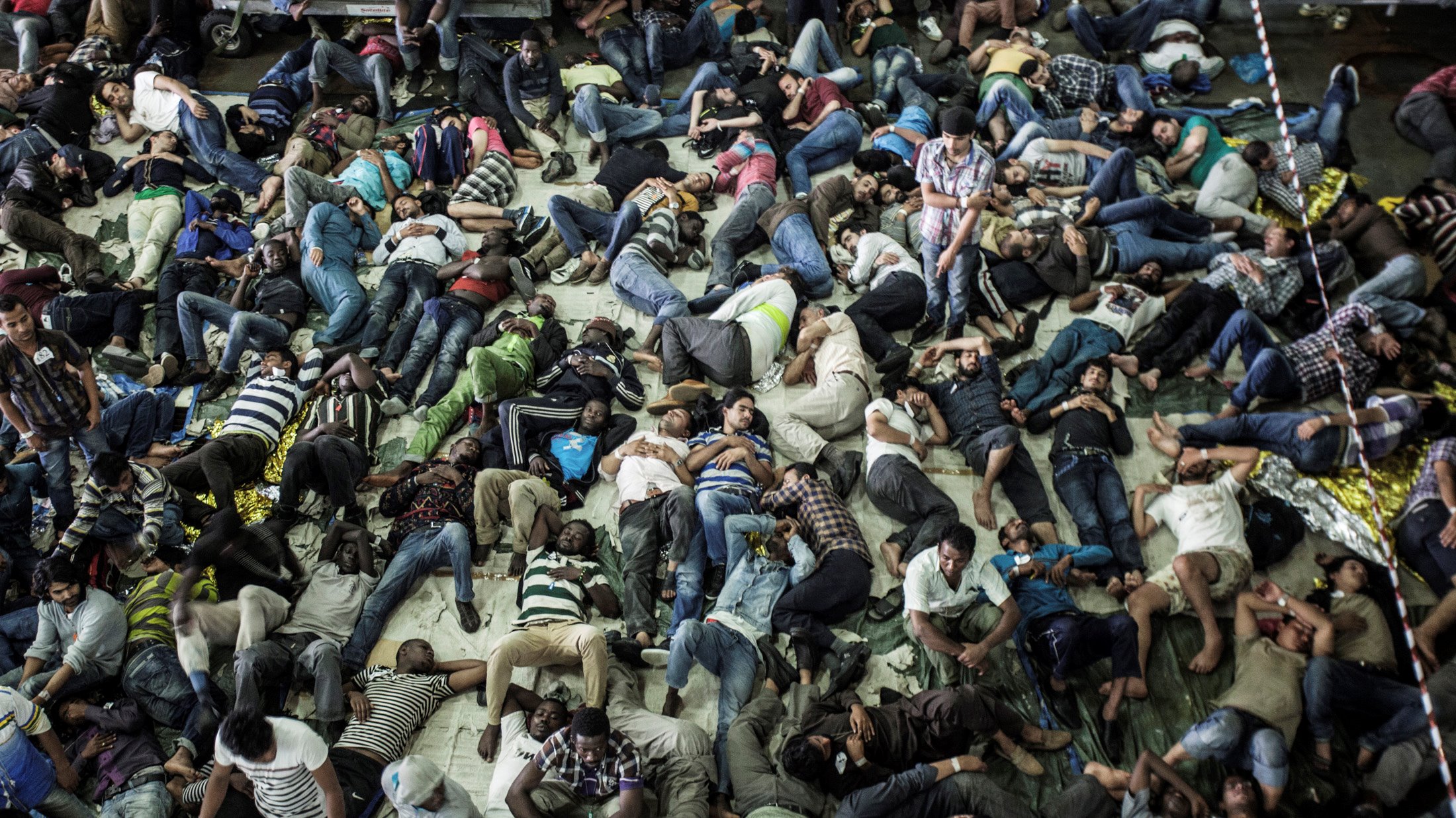 Rescued migrants sleep after being plucked from a boat off the coast of Italy in summer 2014. Thousands of refugees attempt to make the perilous journey to Europe every year, with hundreds dying. In the summer of 2014 the Mare Nostrum search and rescue te