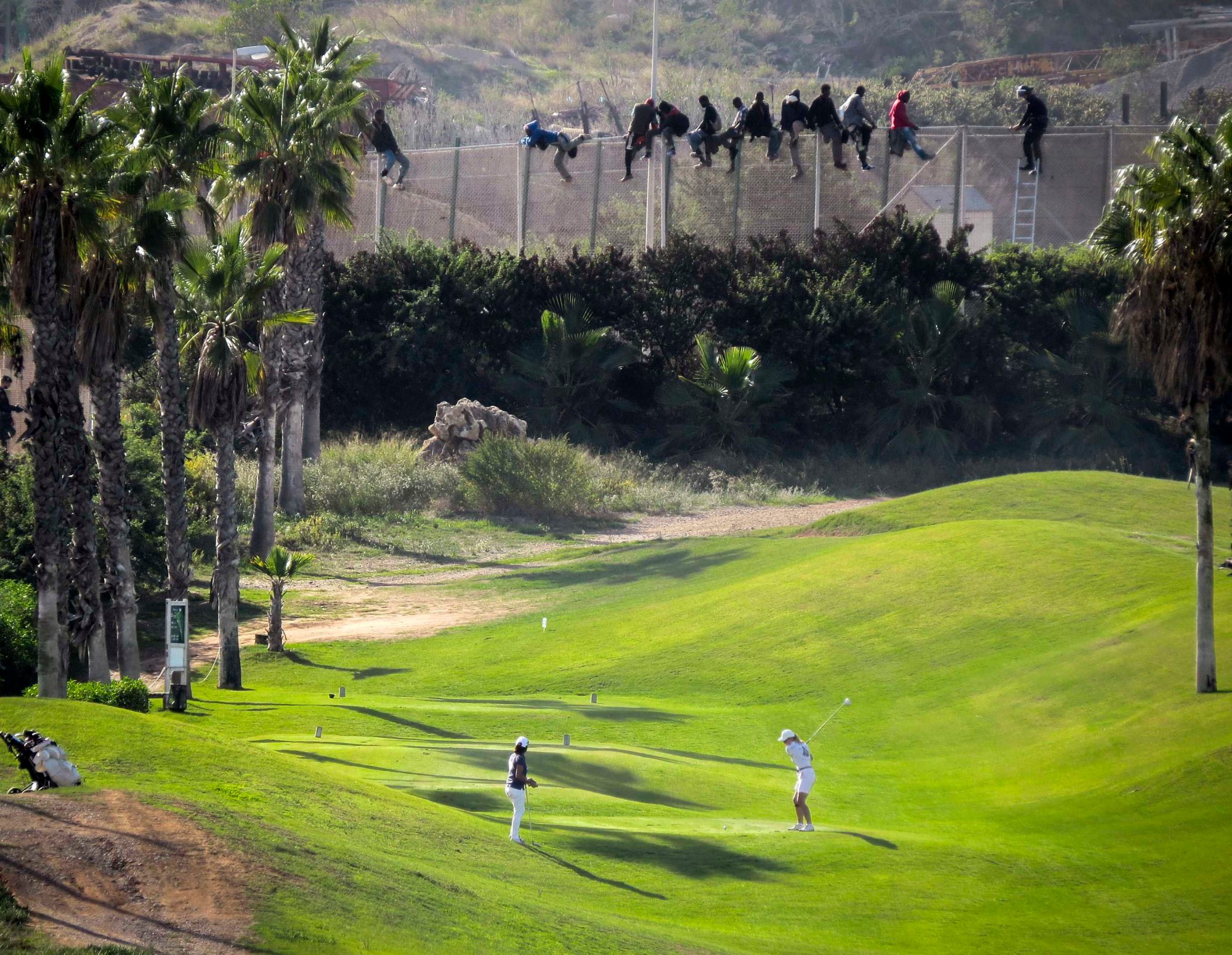 The image of two golfers playing as migrants scale a fence in the Spanish enclave of Melilla, inside Morocco, went viral earlier this year