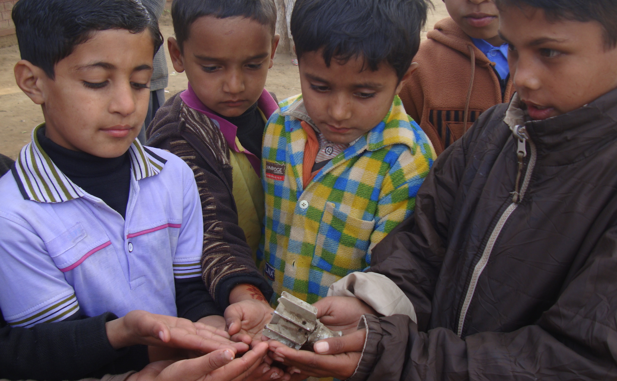 Pakistani children hold the remains of a shell that fell during clashes with India