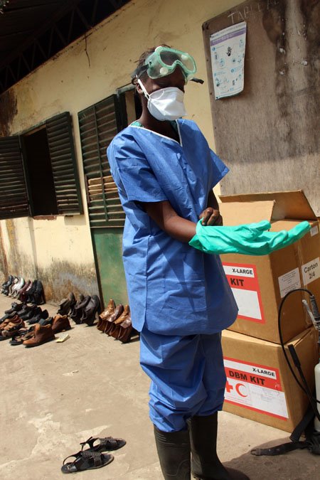 A Red Cross volunteer in Guinea dons protective gear