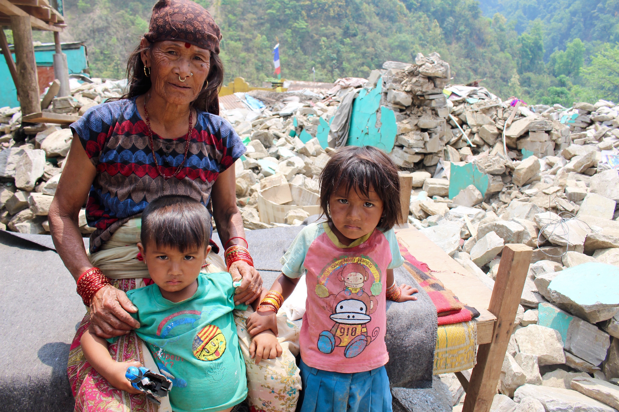 An elderly woman with her grandchildren in the Baluwa market area of Gorkha district, 200 kilometres northwest of Kathmandu. The elderly and children remain most vulnerable to the imminent monsoon season in the wake of the 25 April earthquake that devasta
