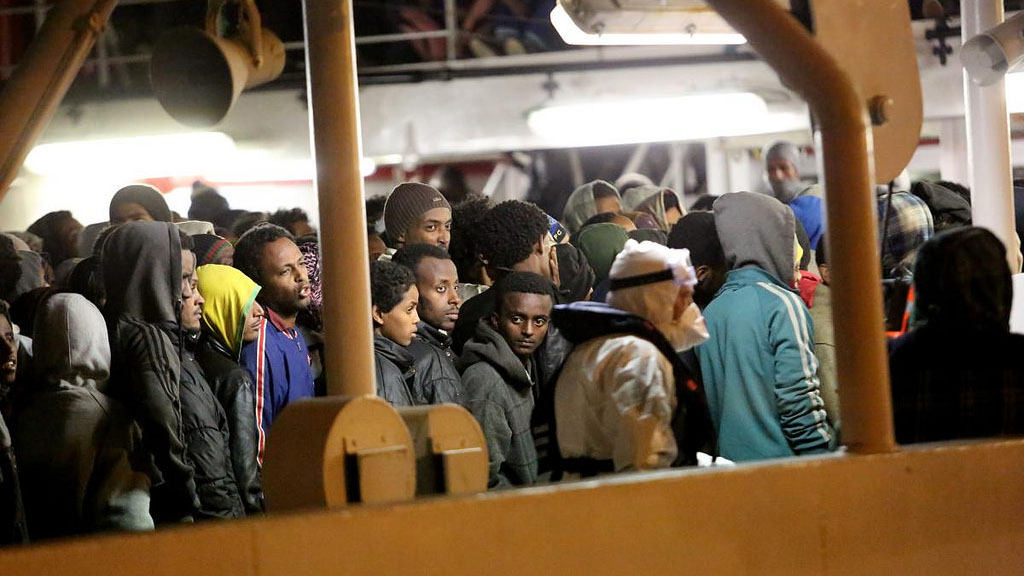 Rescued refugees and migrants wait to leave an Italian Coastguard vessel in Palermo, Italy.