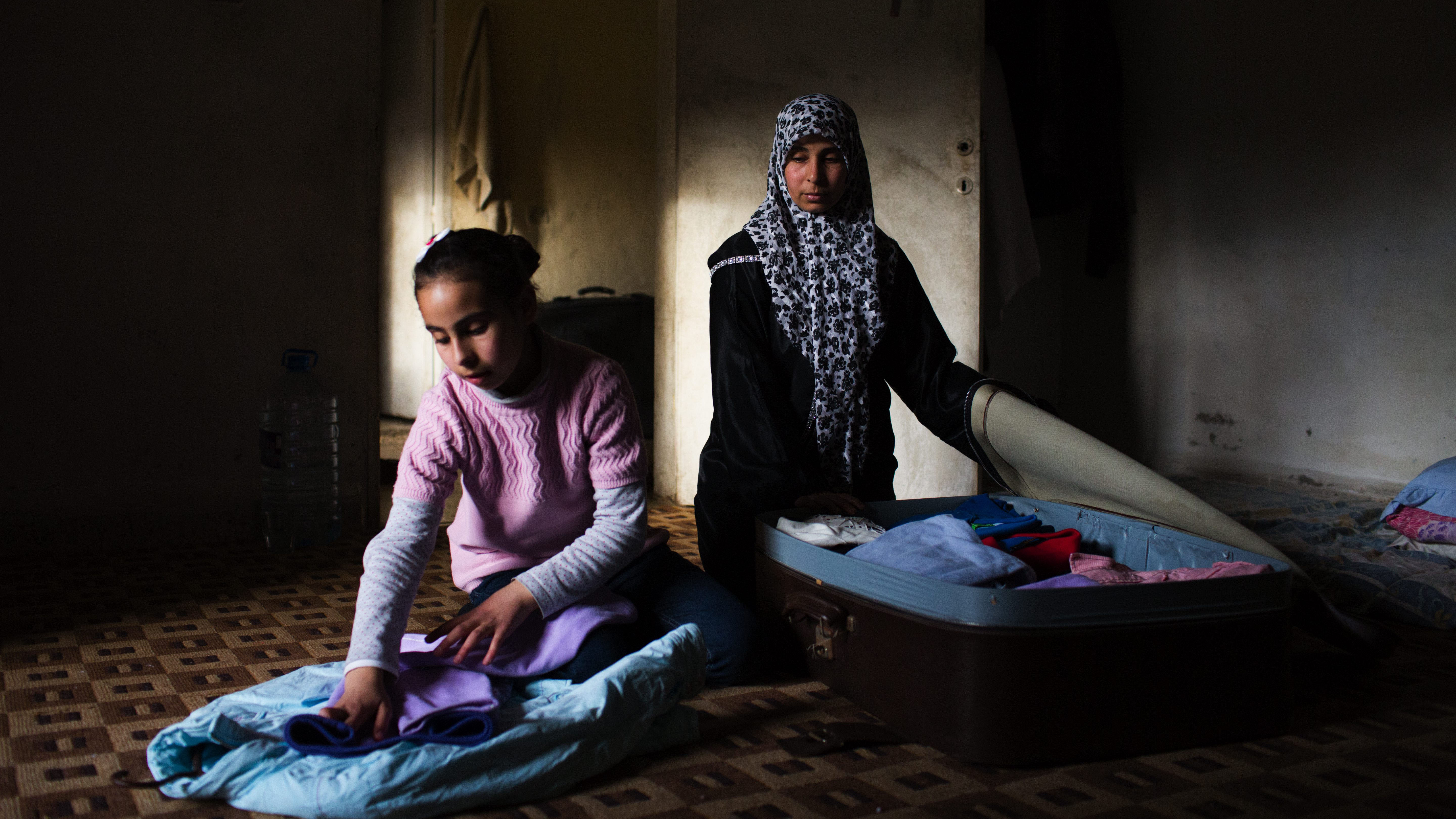 Syrian Refugees, Um Abdullah and her daugther Maysaa, 13, pack a suitcase in preparation for their journey to Gemany, at their temporary home in Barja, Lebanon in April 2014. The family will travel to Germany under the resettlement programme.