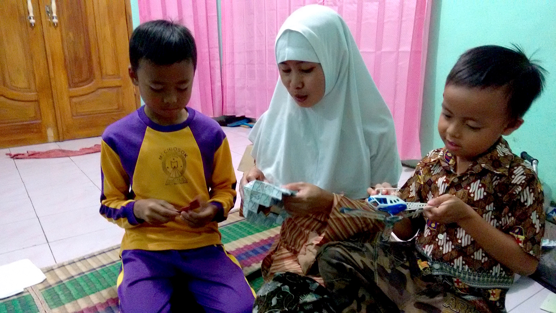 Imas with her sons Alan (left) and Aji who stayed in Indonesia while she worked abroad