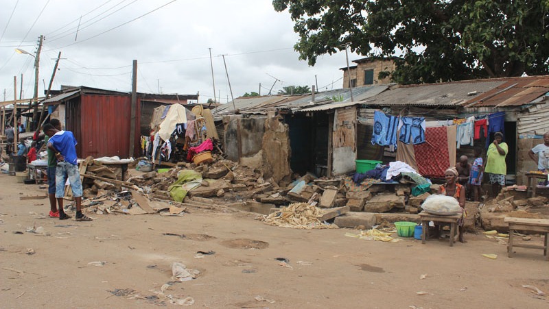 A family sits outside destroyed homes in Accra’s Nima neighbourhood, following heavy rains and flooding on 3 June.