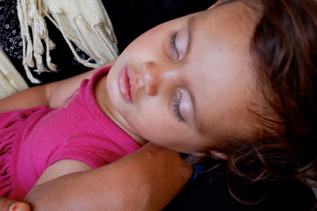 One and a half year old Tabaraq sleeps in her mother's arms during a distribution of relief supplies by the International Committee for the Red Cross in Tuz Khurmatu, Iraq