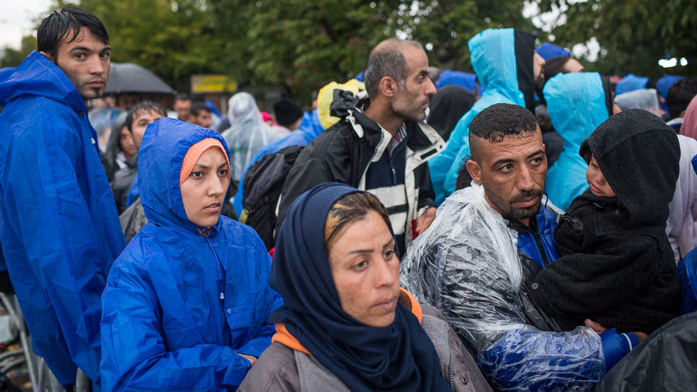 Refugees stand in the rain waiting to register in the town of Presevo in Serbia, after having crossed from Macedonia
