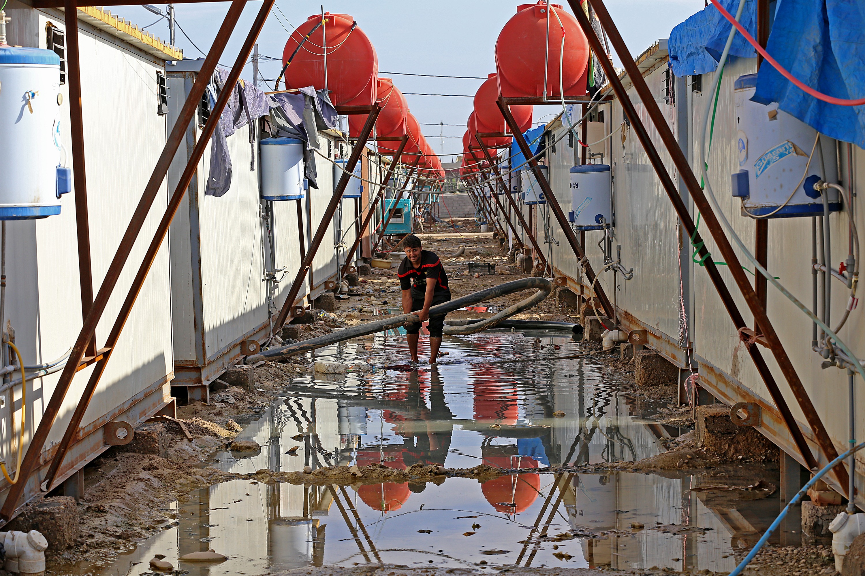 On 04 November a man fixes water pipes while standing in floodwater behind a set of shelters in Nabi Younis IDP camp in Nahrawan, a suburb of Baghdad. Heavy rain in Iraq in late October inundated several areas of the country considered vulnerable to the s