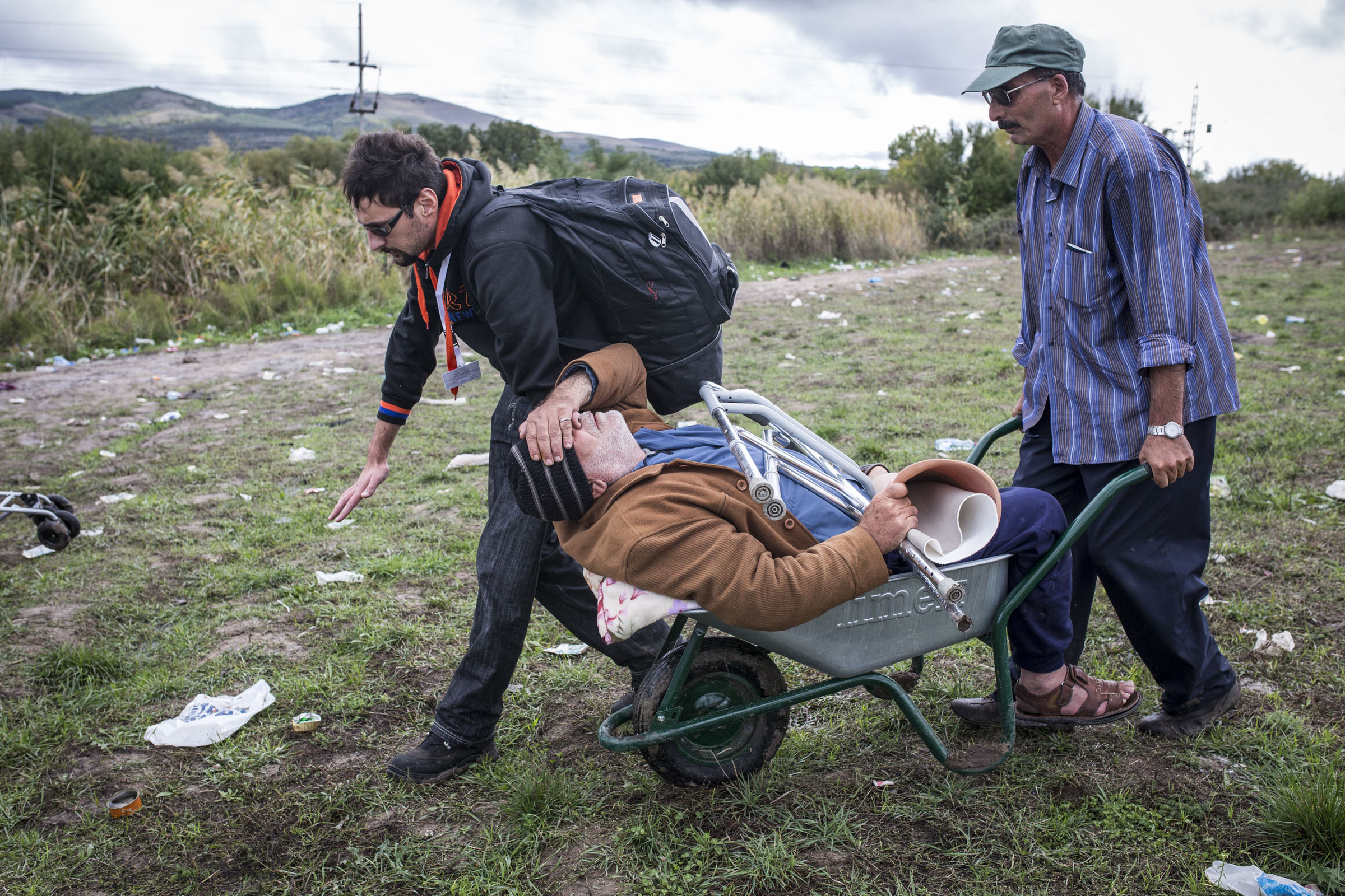 Aid worker, Pane Ignov helps pull Syrian refugee, Bashar, who lost his leg to diabetes, through the no man's land between Macedonia and Serbia