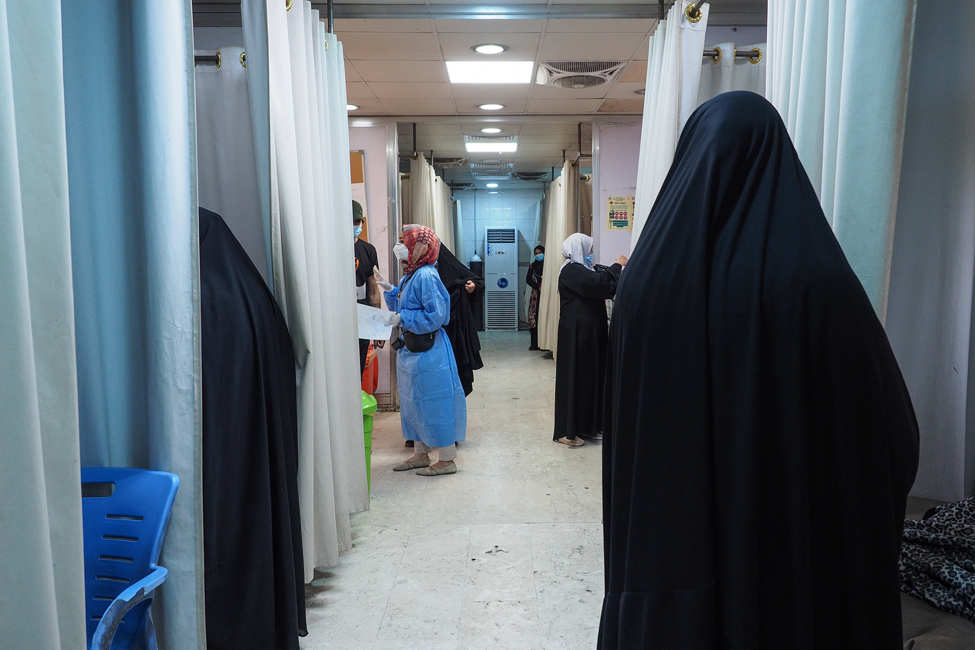 Several people stand in a hospital room.
