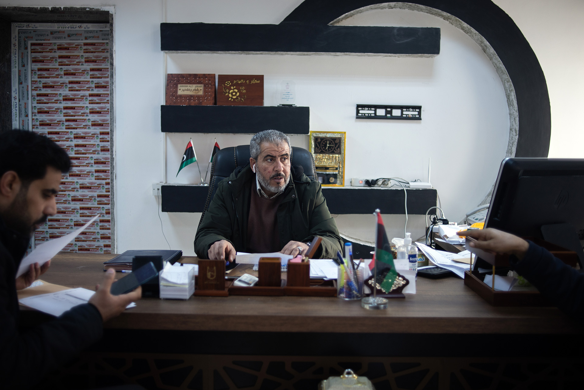 A man is seen sitting behind a large wooden desk in an office.