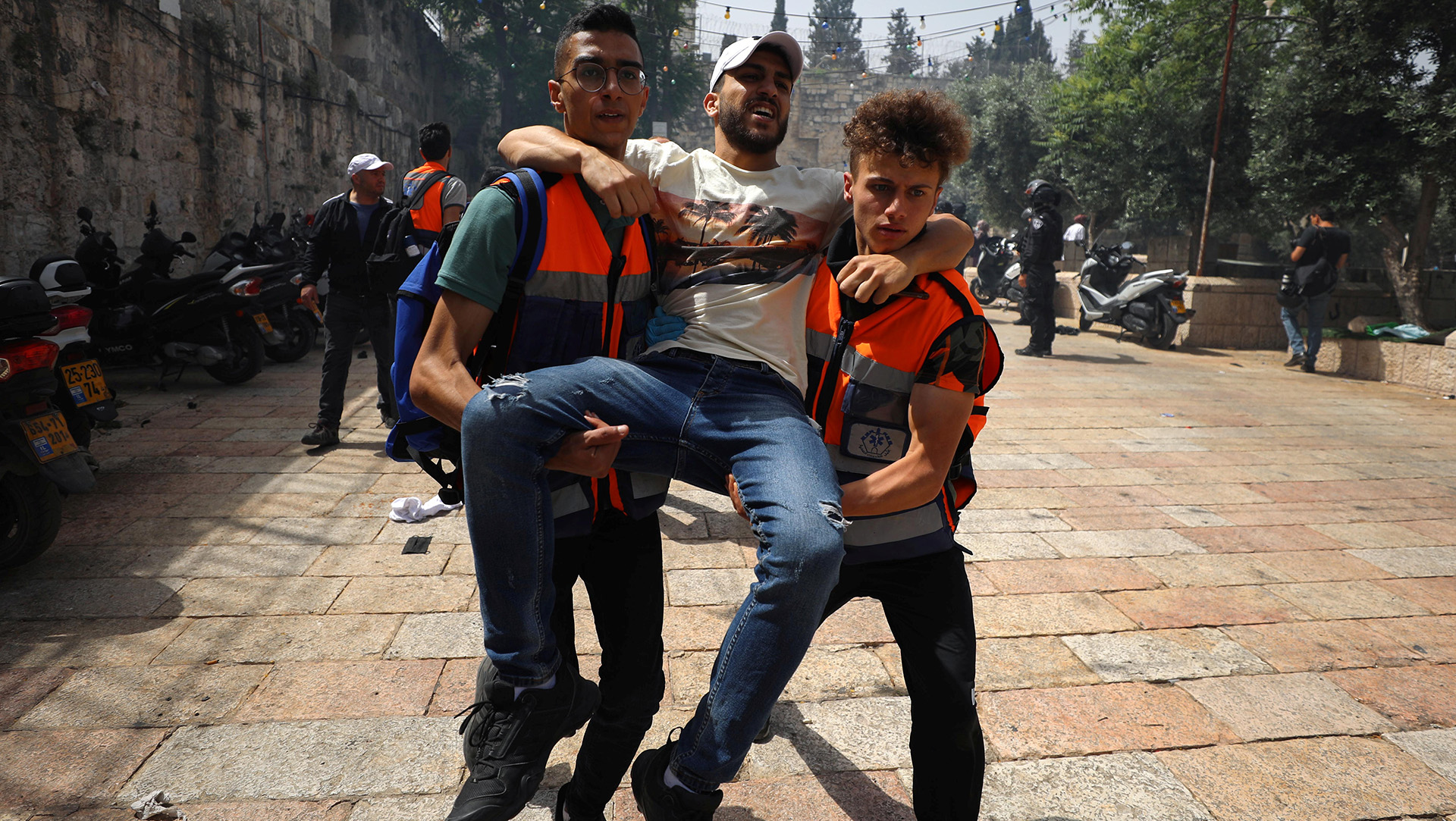 A man is carried by two medics through a street.