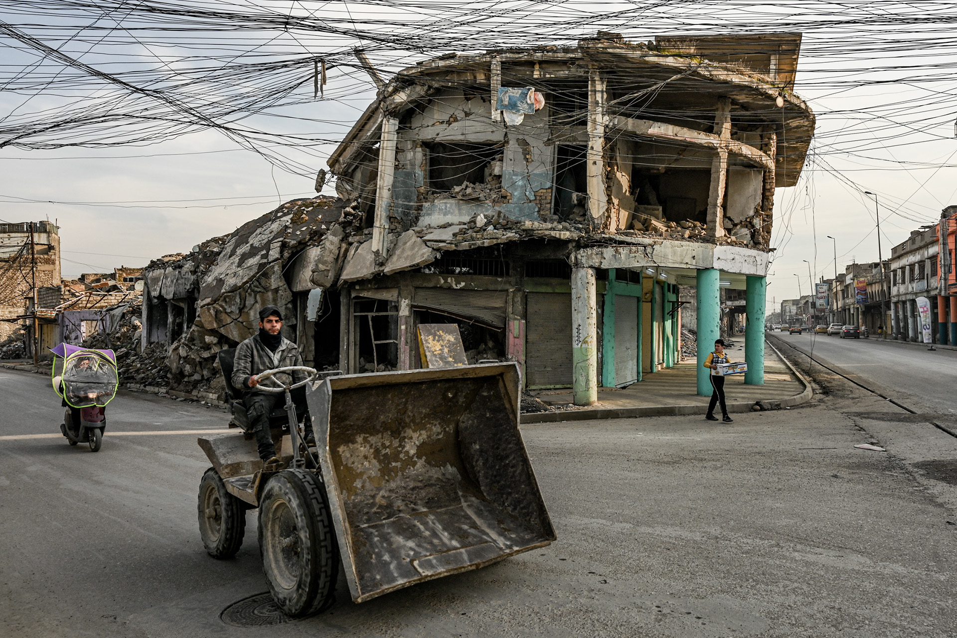 An image of a construction worker driving through a quiet intersection in west Mosul