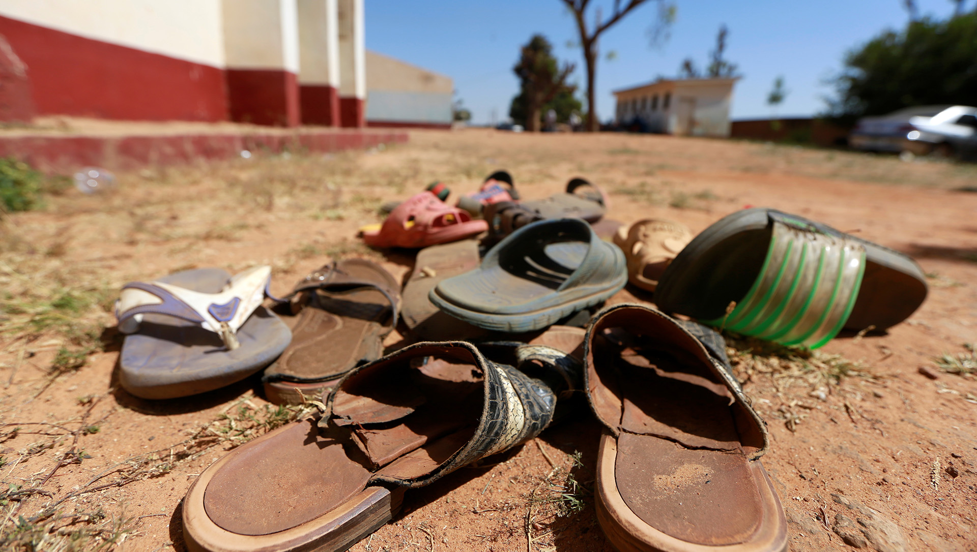 A close-up picture of a pile of shoes on a dirt road.