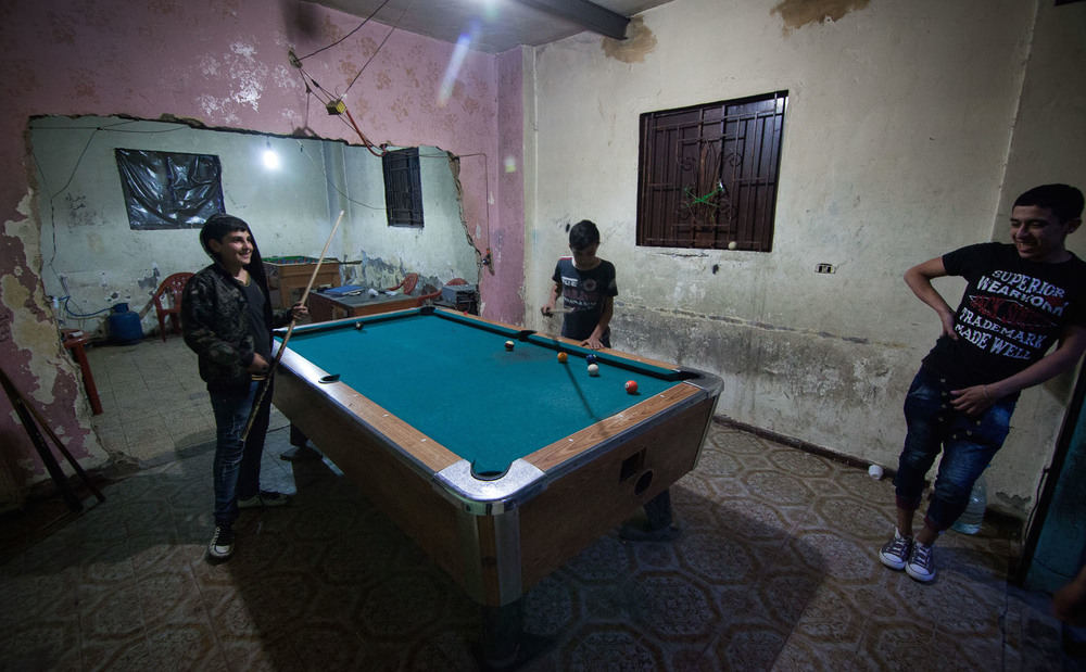 Three smiling young people playing pool