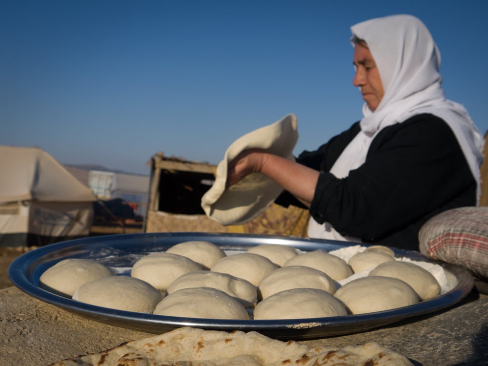 A Yazidi woman prepares bread dough on top of Mount Sinjar