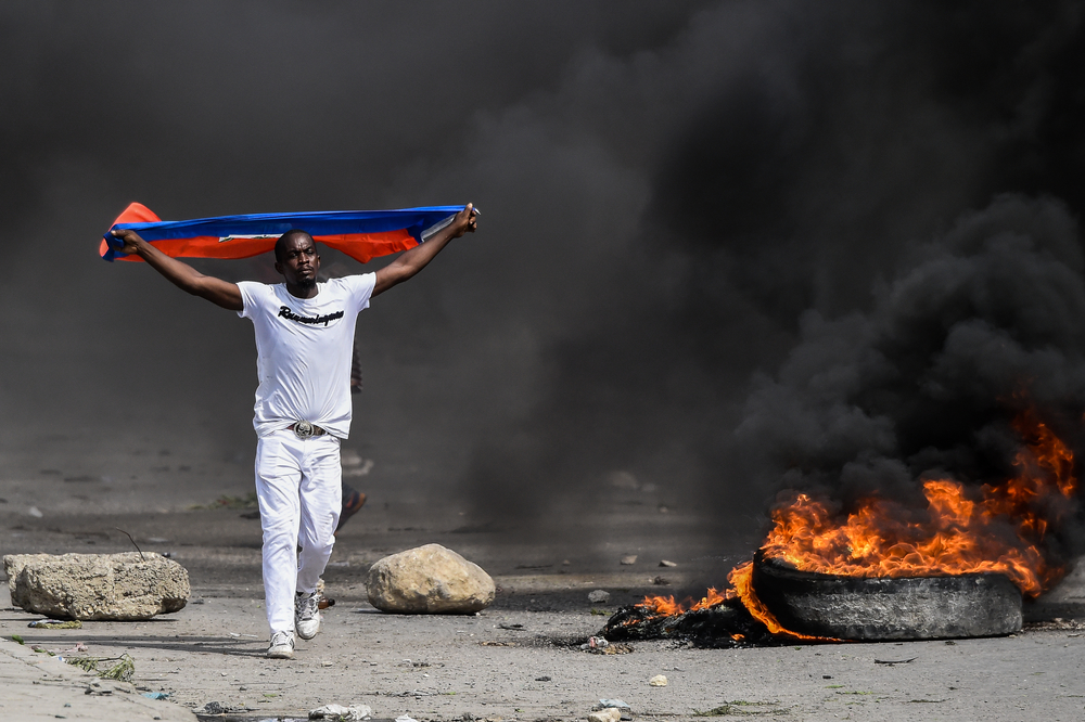 A demonstrator waves a Haitian flag during a protest outside United Nation's main base, against President Jovenel Moise on October 4, 2019 in Port-au-Prince, Haiti.