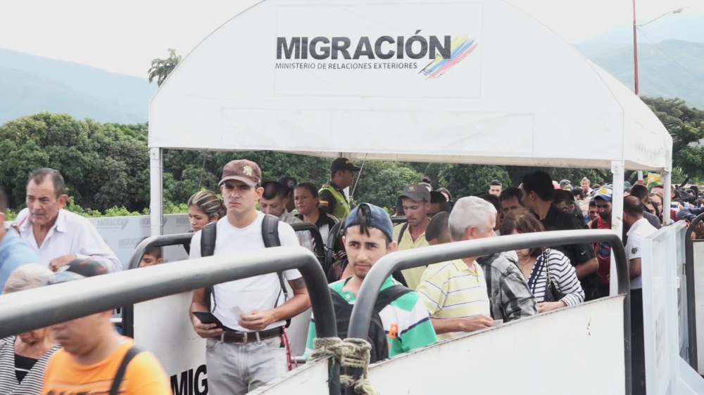 Venezuelans cross the border into Colombia under a sign that reads
