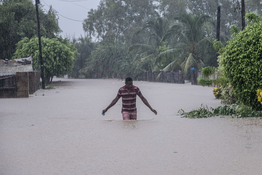 A man stands in the middle of a road with water up to his thighs