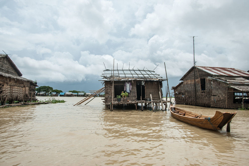 Houses on stilts surrounded by water with a canoe moored to the center house.