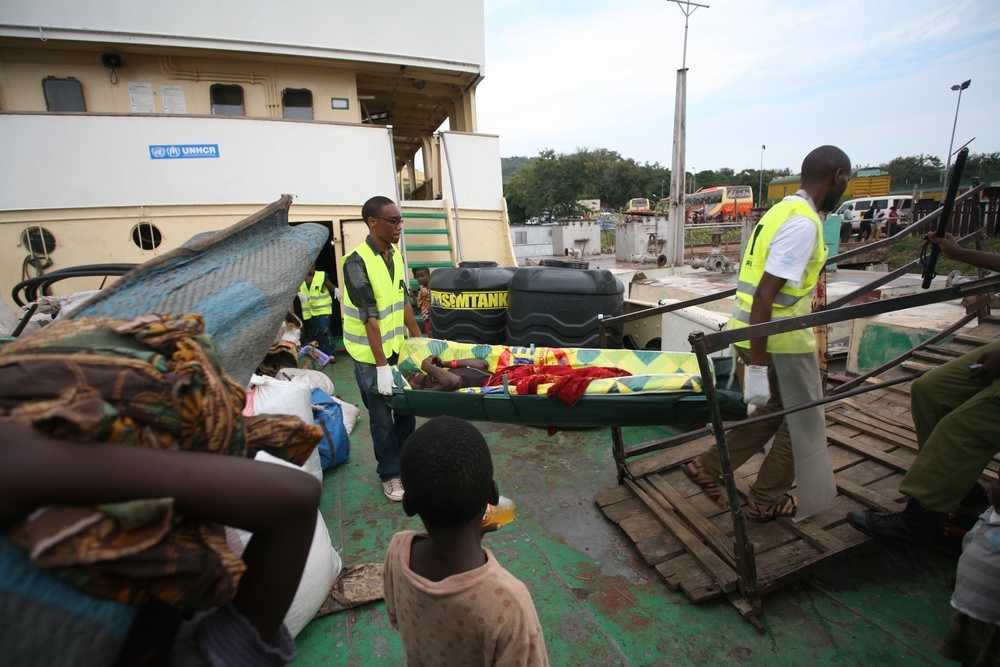 A male Burundian refugee with suspected cholera is carried off the MV Liemba in Kigoma, Tanzania, by staff of the International Rescue Committee