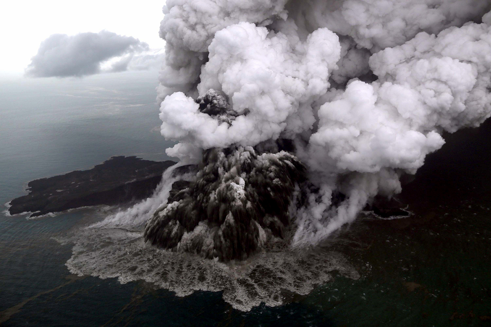 Aerial footage of a volcano erupting, ash billowing