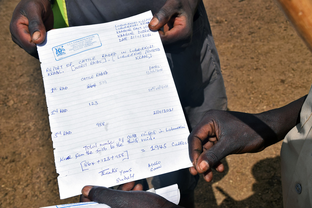 A hand holds out a white piece of lettered paper scrawled in notes.