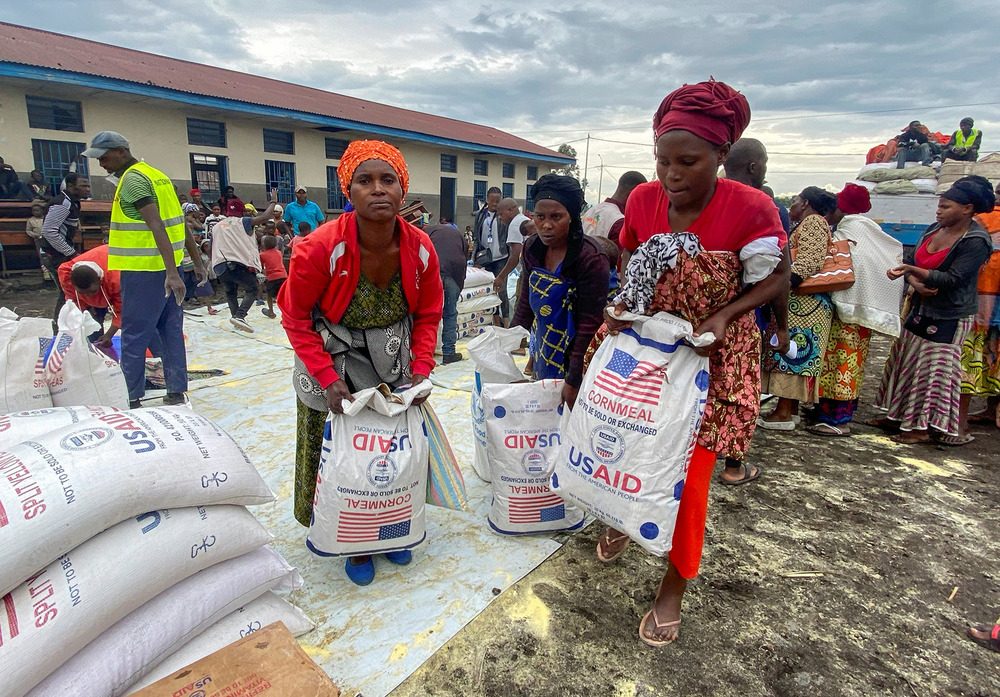 Displaced Congolese women carry bags of food aid from a distribution centre after escaping fighting near the border with Rwanda. Insecurity is hindering relief efforts as the M23 insurgency gathers steam.
