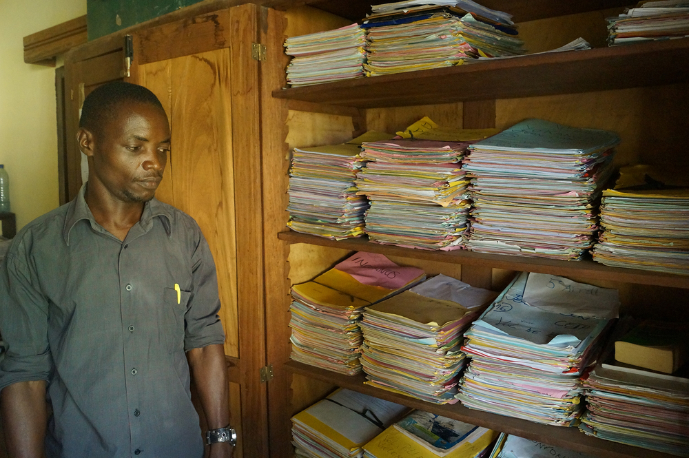 A man stands in front of shelves full of files stacked