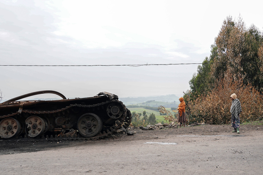 Residents walk past an abandoned tank on a main road in Amhara region. Fighting has intensified in recent days after the government launched a fresh anti-rebel offensive.