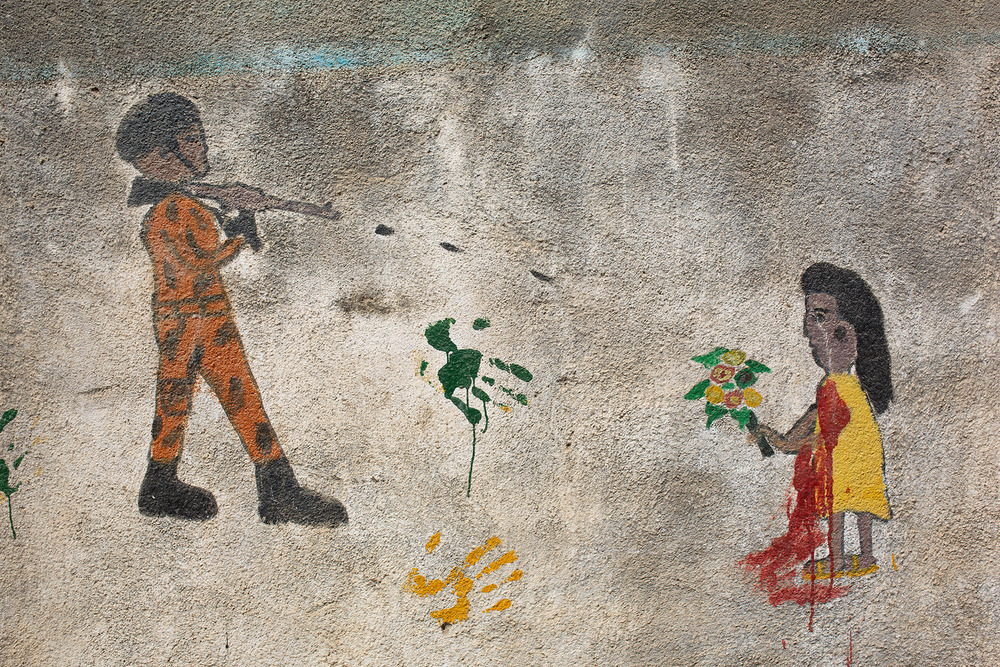 Graffiti shows a soldier shooting a civilian on a wall.