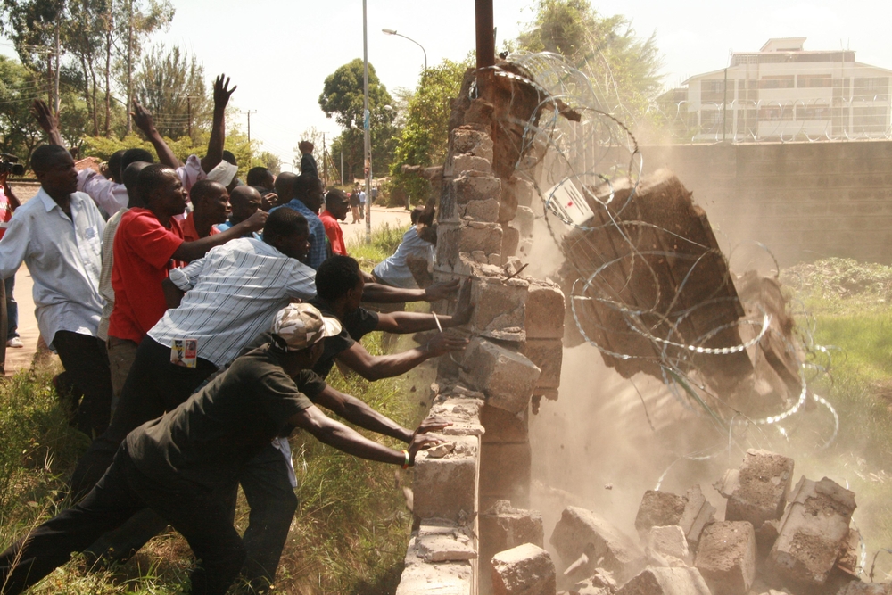 Irate youth demolish the wall of Telkom Kenya after a funeral service that was organised by the opposition ODM, Nairobi, Kenya, January 2008. The crowd was later dispersed by police through the use of tear-gas.
