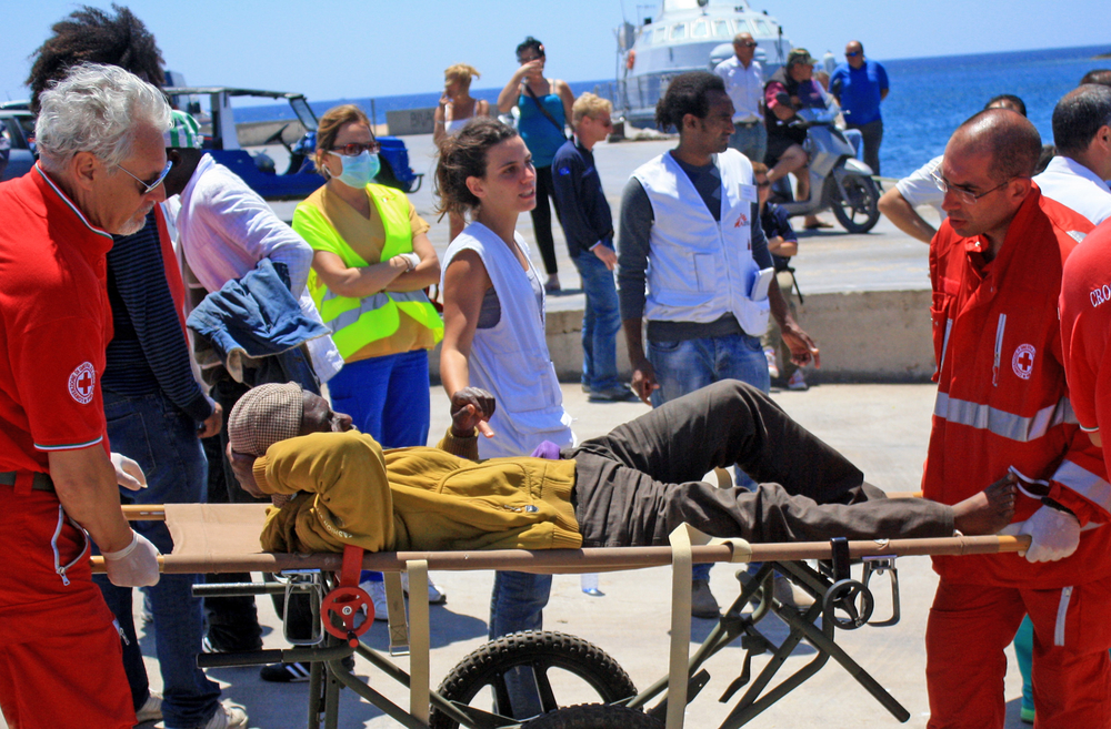 Paramedics from the Italian Red Cross treat an injured migrant worker at Lampedusa's port