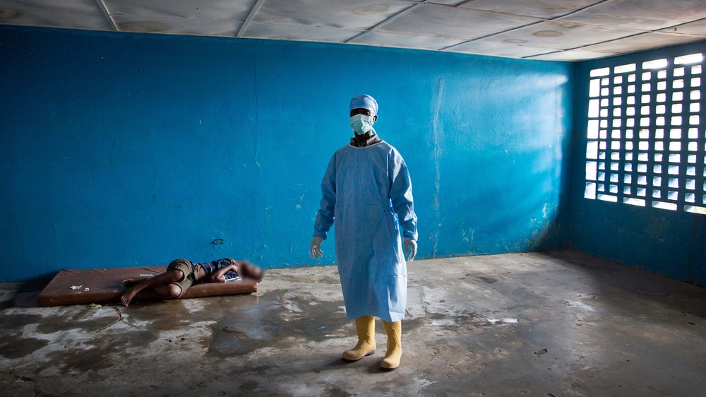 A healthcare worker stands next to a woman who had died of Ebola related symptoms. (Sep 2014)