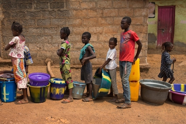 Children queue with containers to receive with water, in the city of Kenema in Kenema District, Sierra Leone. March 2014