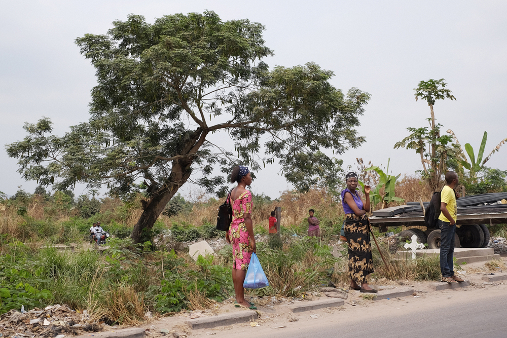 Locals wait for transport among gravestones