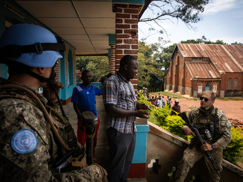 Des Casques bleus discutant avec le prêtre d'un camp de déplacés pour civils fuyant les combats dans la province congolaise d'Ituri, en novembre 2021.