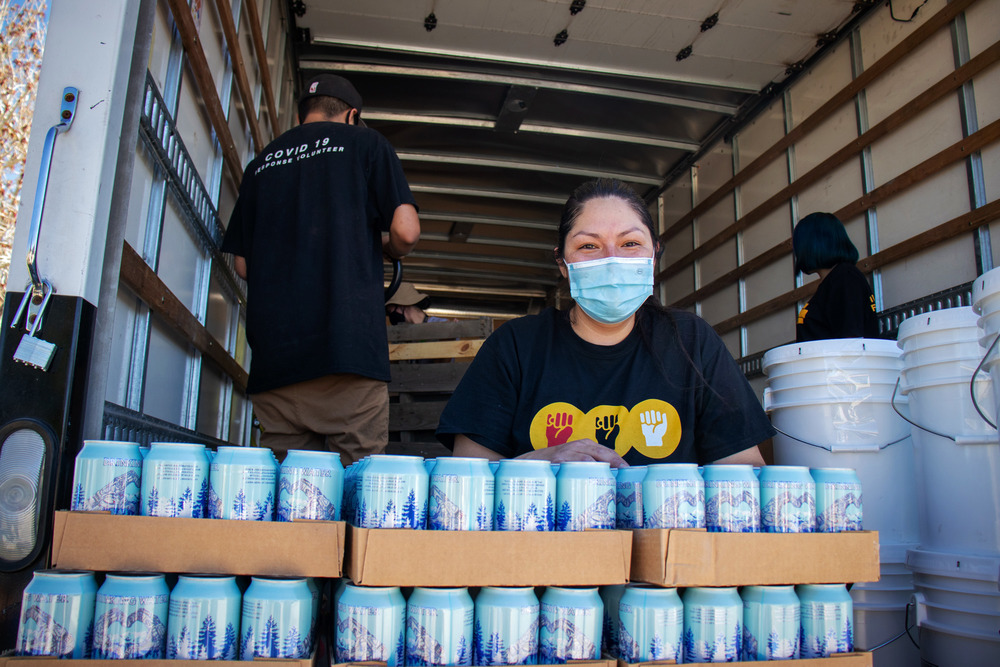 Krystal Curley, executive director of Indigenous Lifeways, unloads cans of water for distribution. Her non-profit delivers essentials to parts of the reservation where water and electricity are scarce.