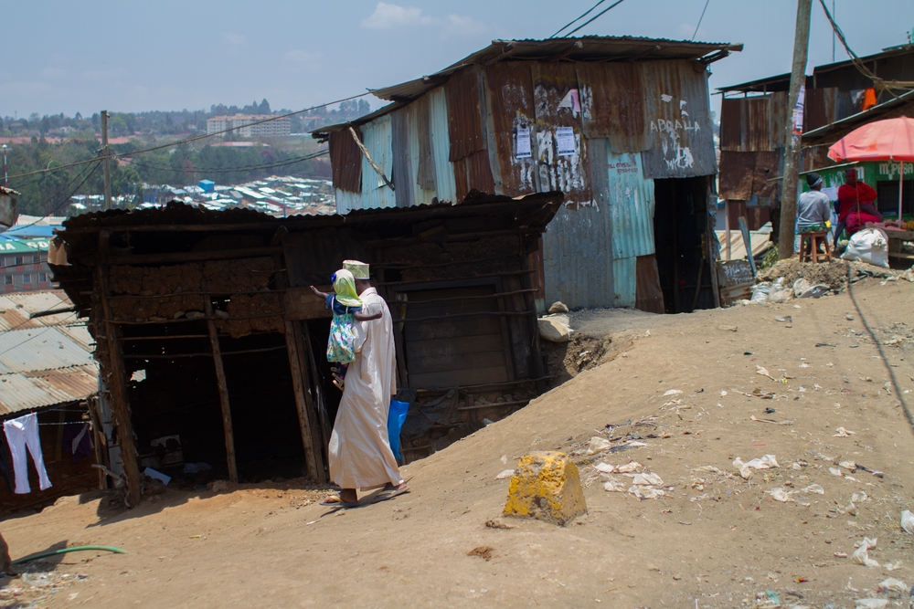 A man carries his daughter in Kibera