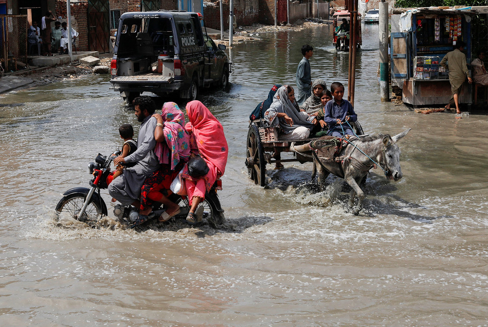Commuters travel through floodwaters in Jacobabad, in Sindh province, on 30 August 2022.